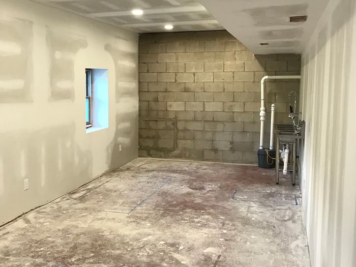 Unfinished room with drywall, exposed block wall, recessed lights, and plumbing.